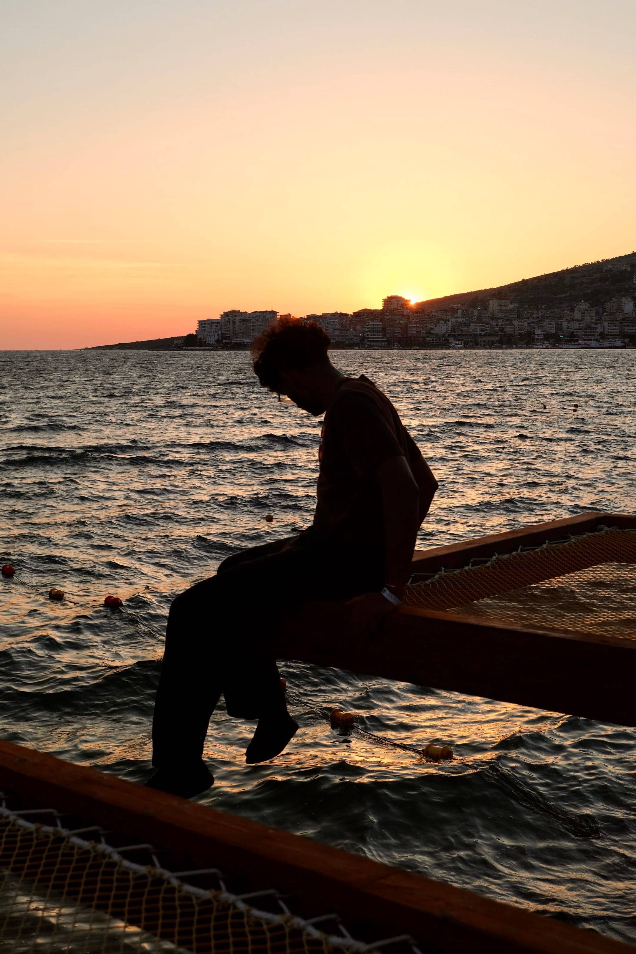 Krish sitting on a jetty at sunset